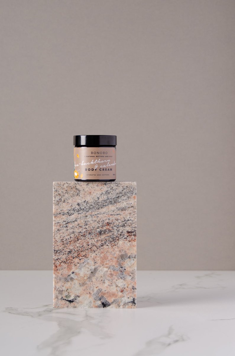 BONOBO Body Cream med havtorn och ringblomma i glasburk med svart lock, fotograferad på marmorblock