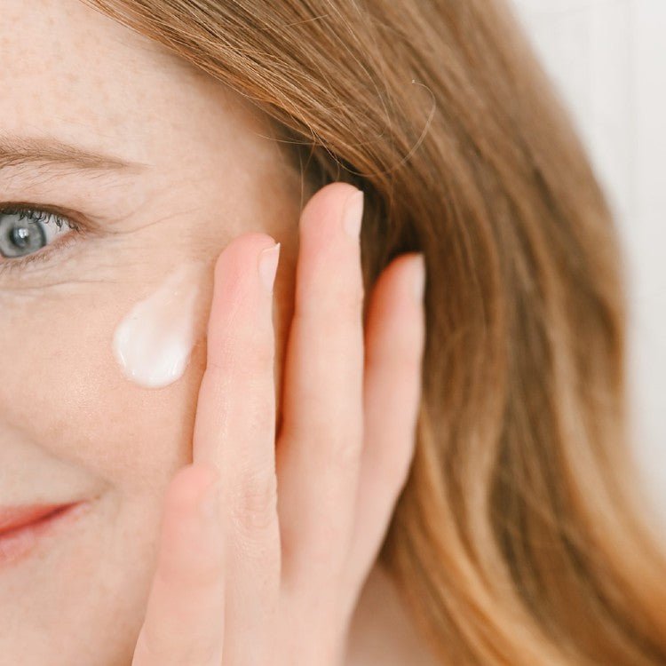 Kvinna applicerar vit kräm på ansiktet med handen, visar texturen av Nourishing Face Cream för mogen hud