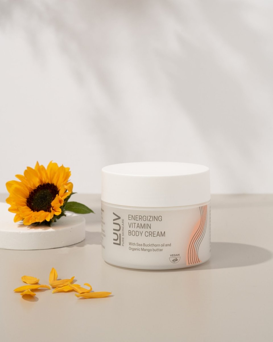 Vit burk med Body Cream Havtorn & Morot på marmorbakgrund med gul solros och kronblad