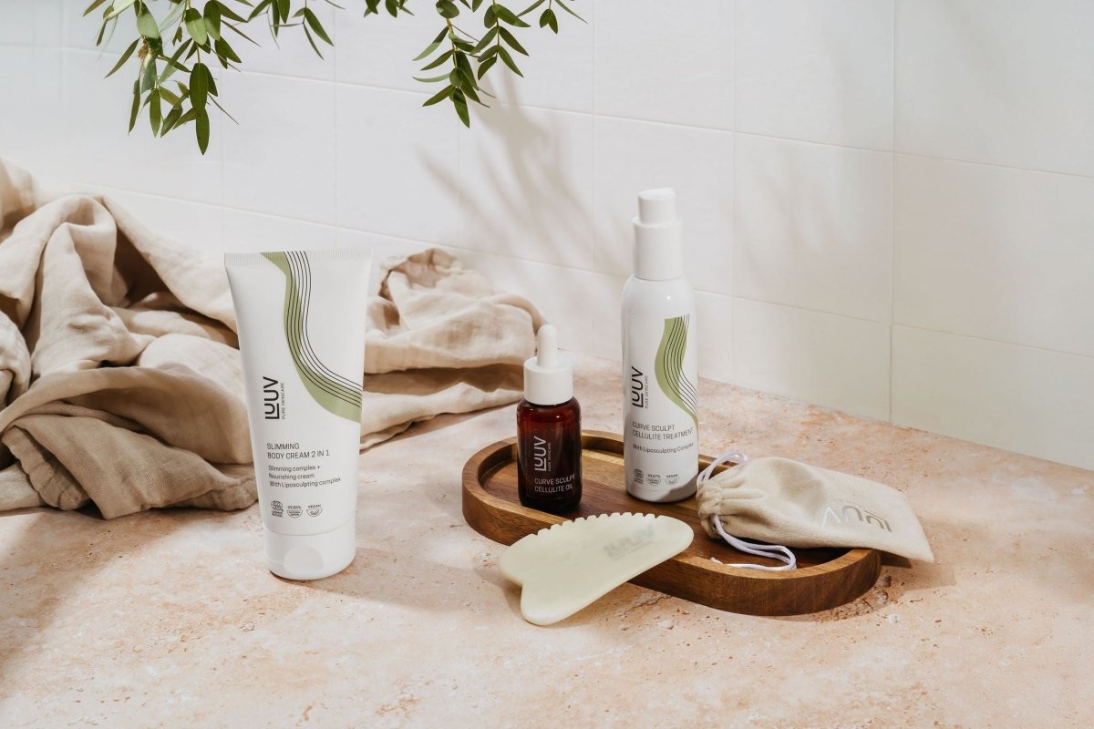 Cellulite Treatment COSMOS 150ml i vit flaska med pump, tillsammans med kroppskräm och gua sha-verktyg på träbricka