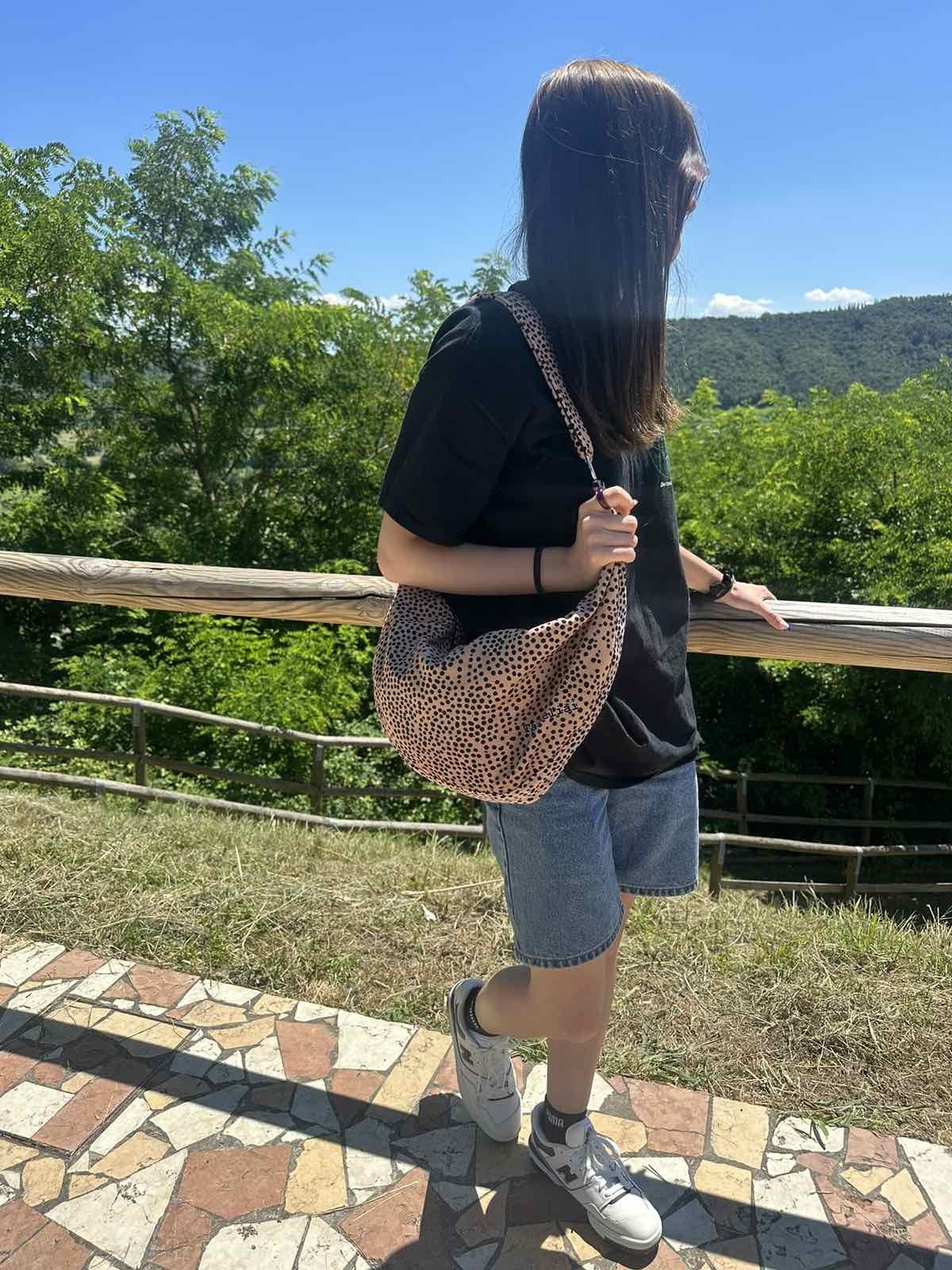 Hobo Bag Cream and Dots - beige väska med svarta prickar, buren över axeln av kvinna i svart t-shirt och jeans