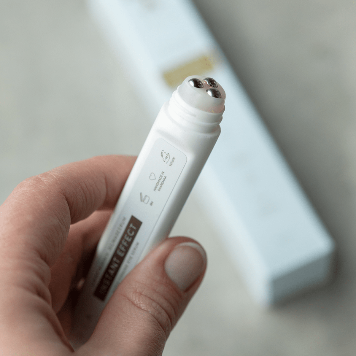 HOIA Superfirming Eye Serum med Bakuchiol i vit cylindrisk förpackning med metallisk applikatorspets hålls i hand