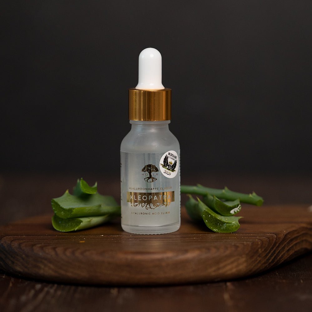 HOIA Kleopatra hyaluronsyra serum i glasflaska med pipett, omgiven av färska aloe vera-blad