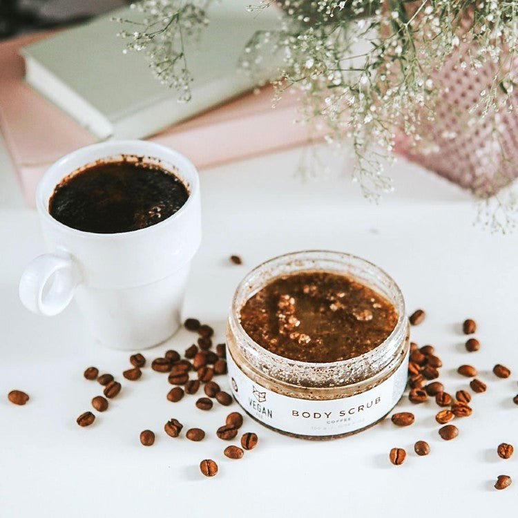 Coffee Body Scrub 300g i öppnad glasburk med brun kaffescrub, omgiven av kaffebönor och kaffekopp