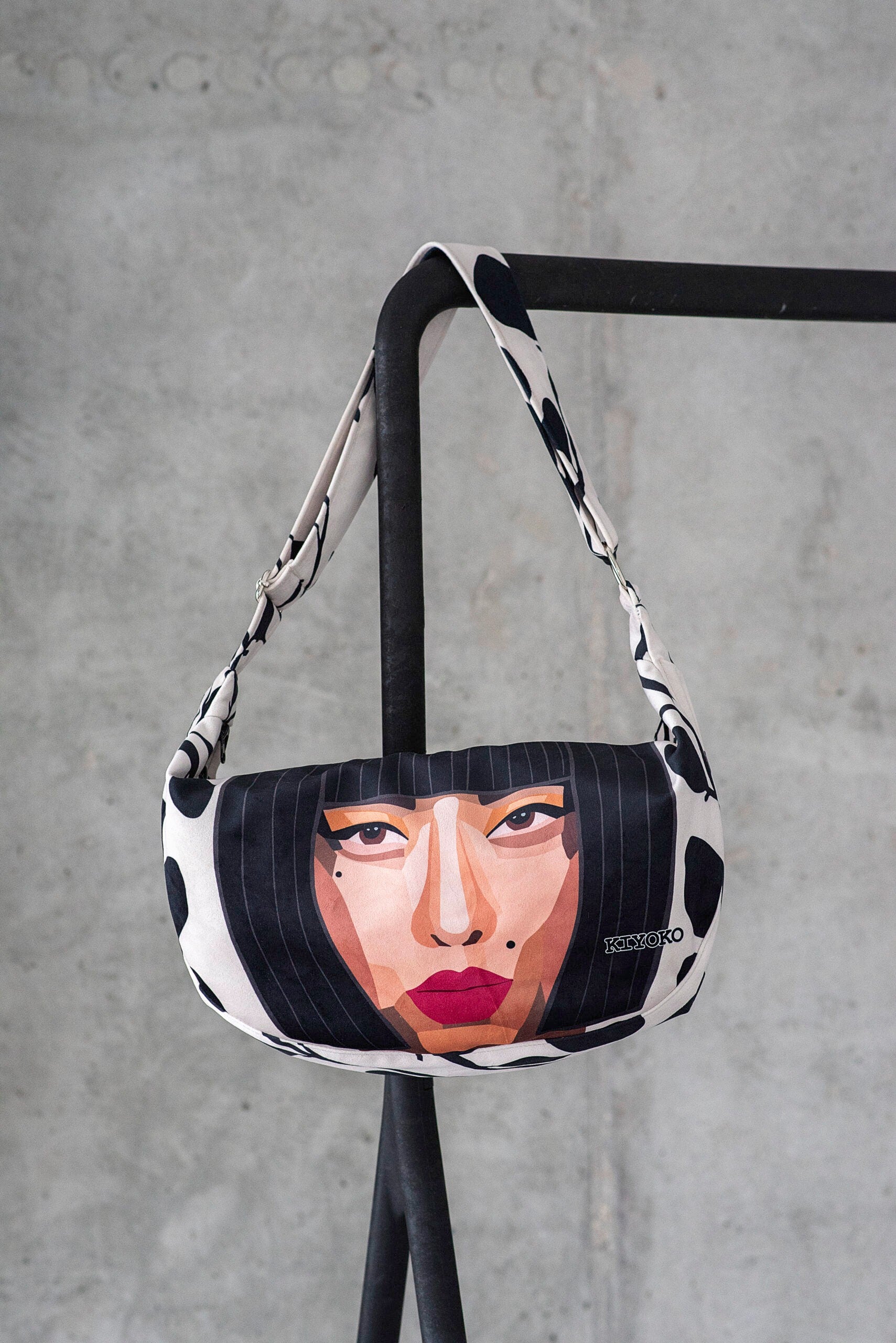KIYOKO Hobo Handväska i vit mocka-look med svart mönster och ansiktsmotiv, hänger på svartställning