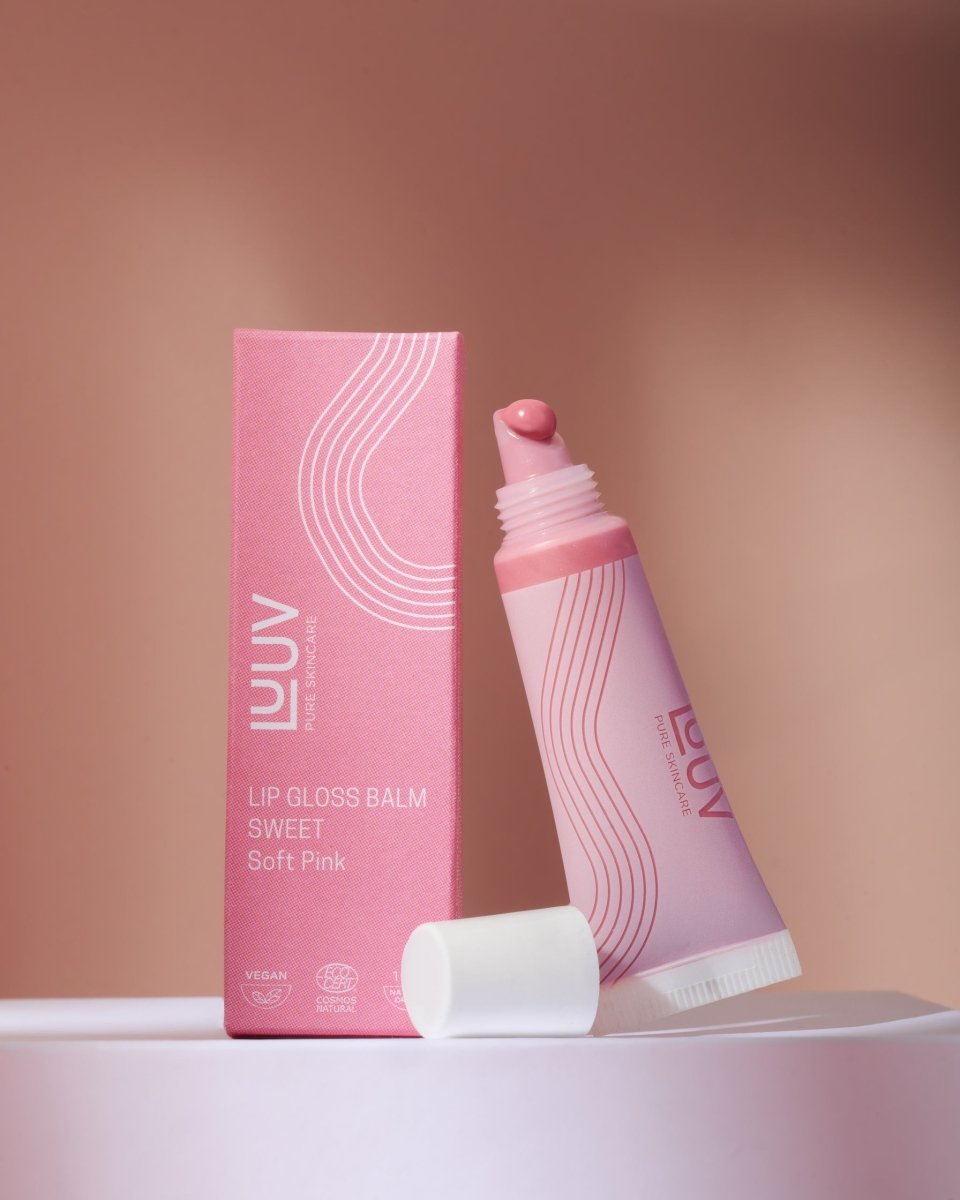 Läppbalsam Sweet i rosa tub med vit kork bredvid rosa förpackning med våglinjemönster
