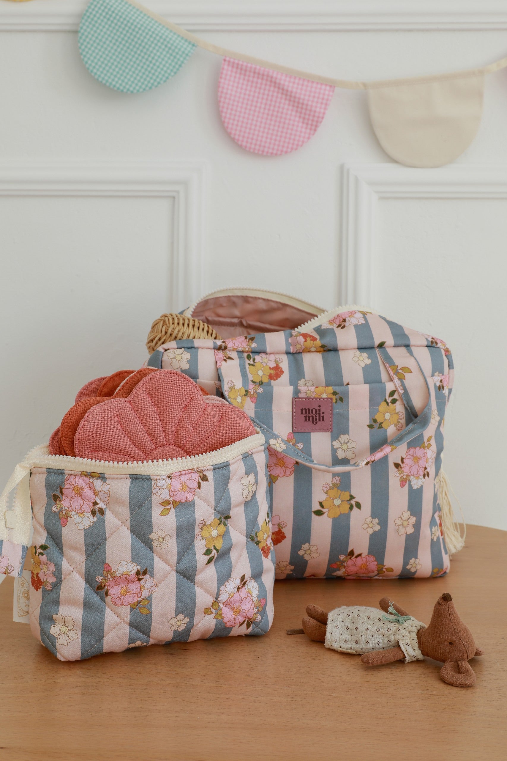 Large Make-Up Bag Blue Stripes med blå-rosa randigt tyg och blommönster, öppnad med rosa necessärer synliga inuti