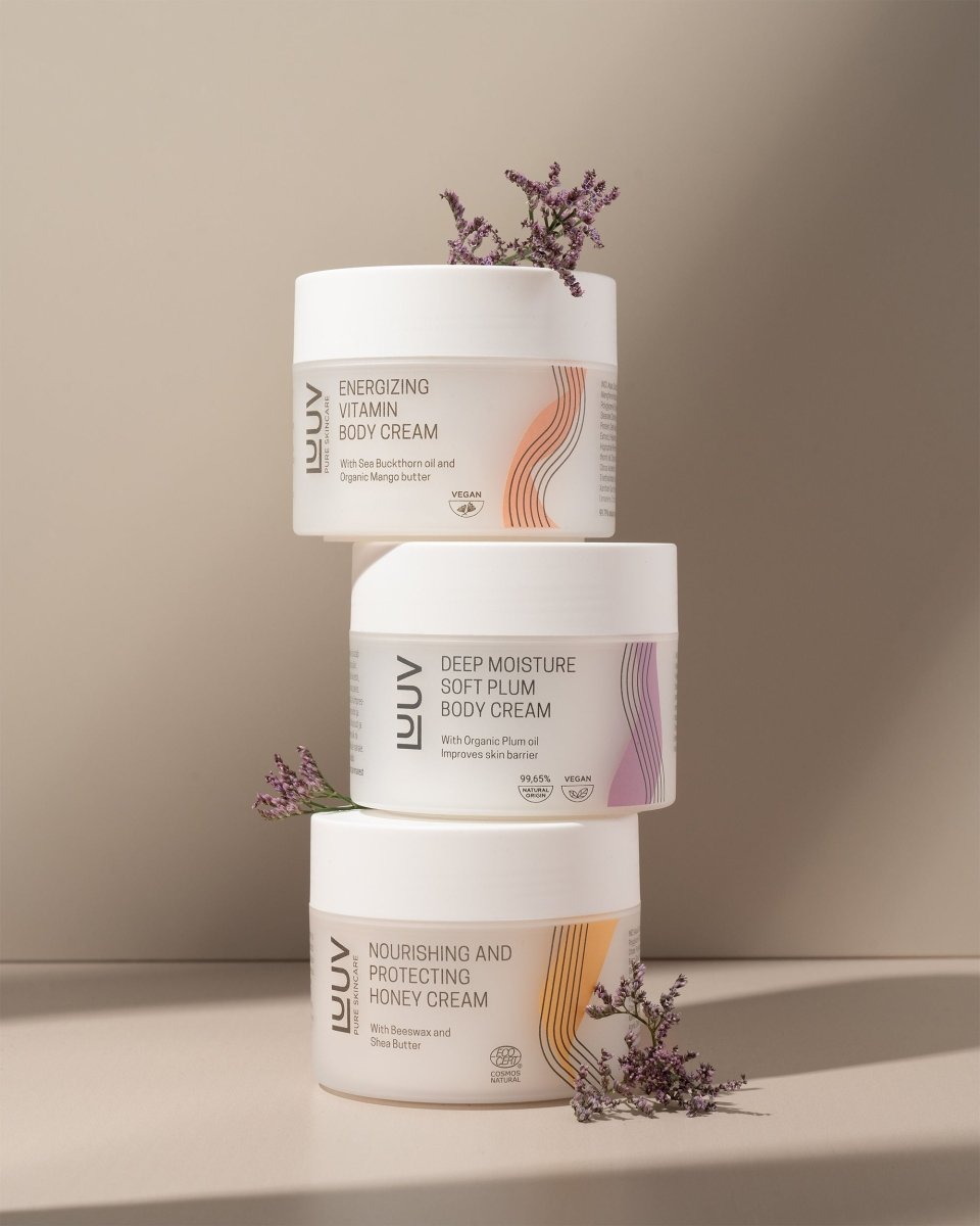 Närande och skyddande honungs body cream i vit burk med orange vågor på etiketten, staplade med andra produkter