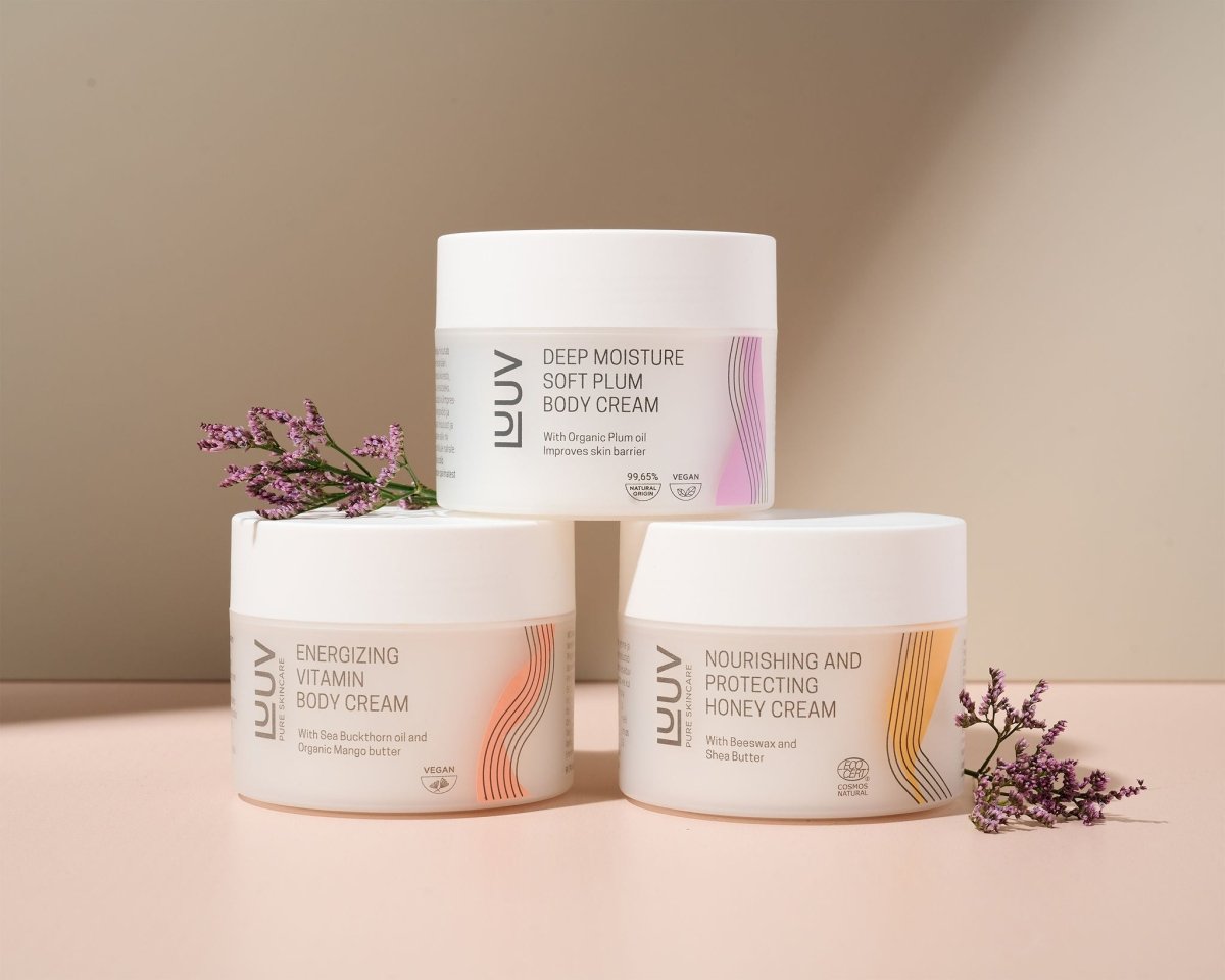 Vit burk med naturlig djupt fuktgivande body cream med plommonolja, runda förpackningar med rosa detaljer på beige bakgrund
