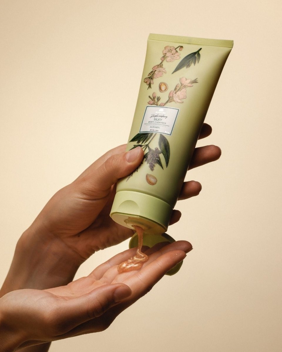 Magrada X Lauren Moisturizing Shower Gel i grön tub med blommönster hålls i hand medan persikofärgad gel pressas ut