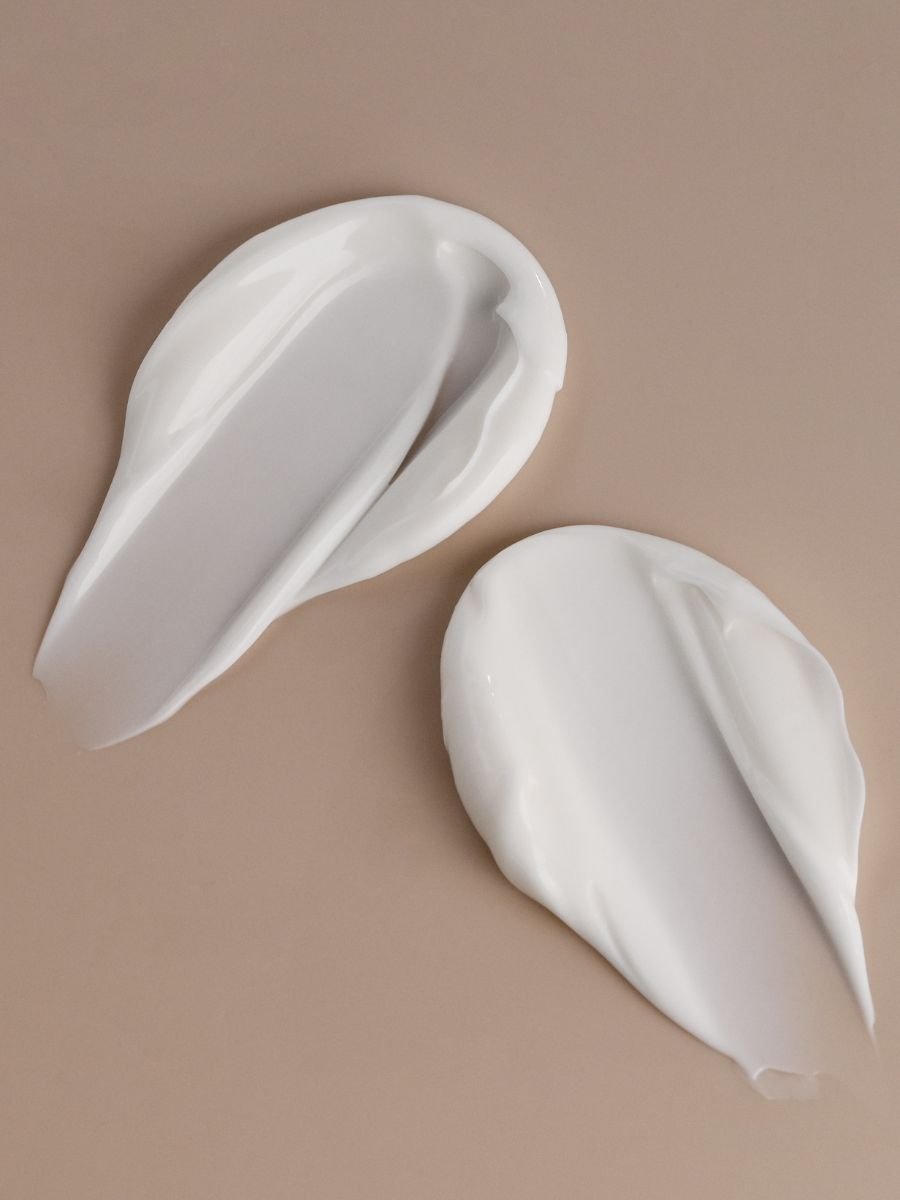 Två vita cremeklickar av Magrada X Lauren Replenishing Body Balm på beige bakgrund visar den rika texturen