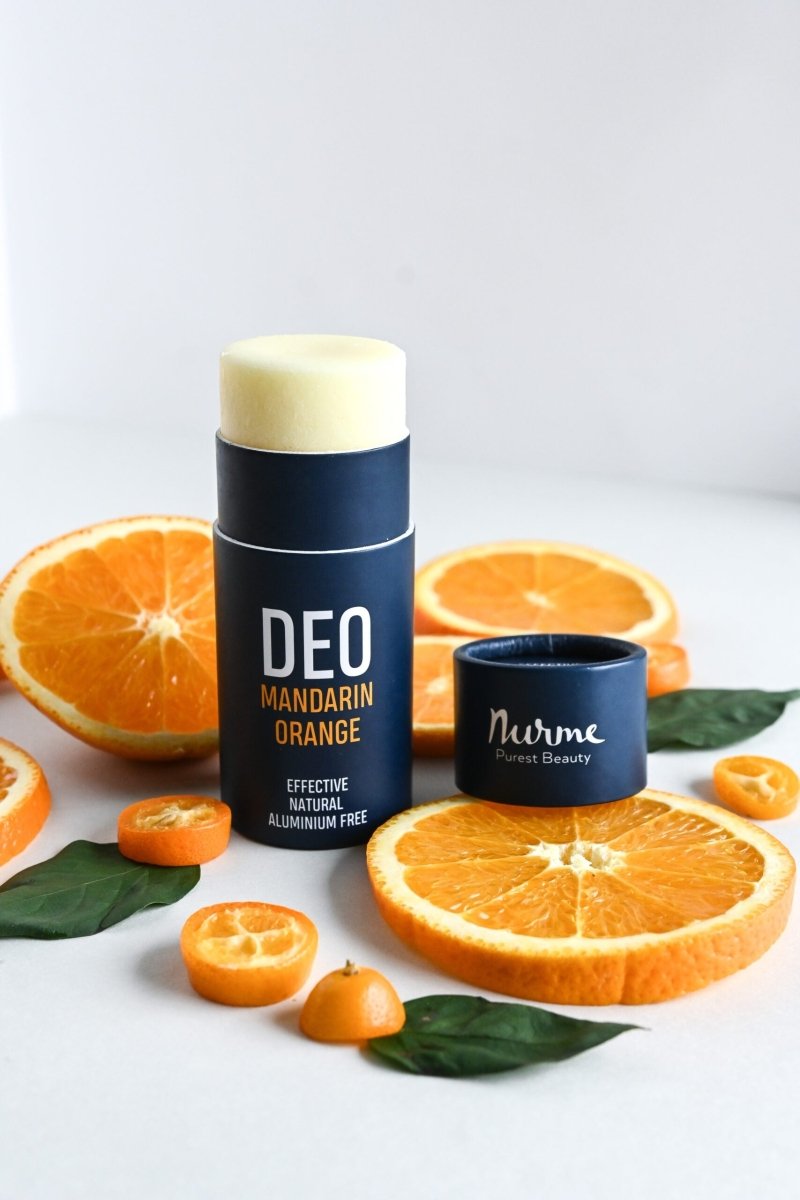 Nurme naturlig deodorant i blå stick-förpackning med gul produkt, omgiven av apelsinskivor och mandariner
