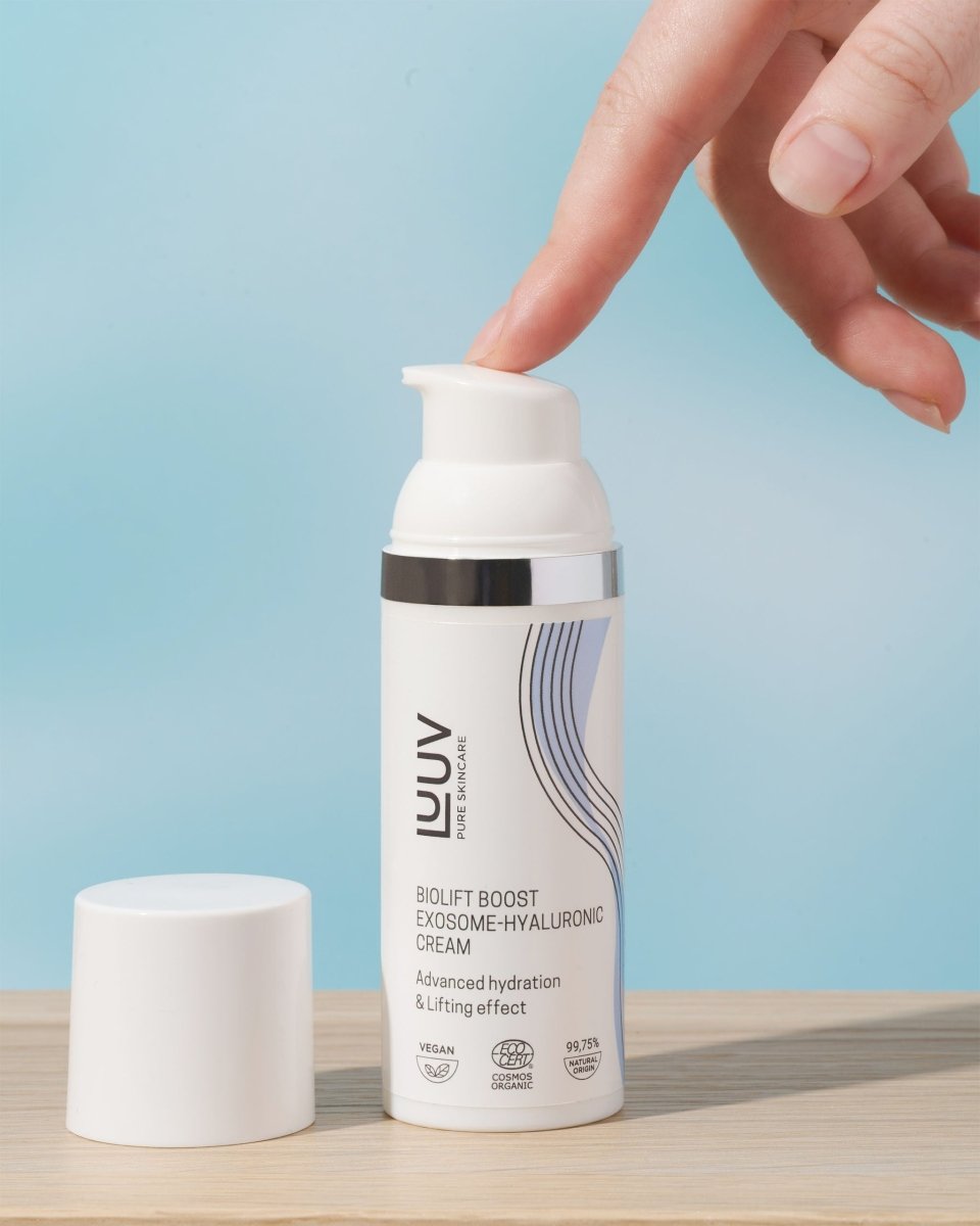 LUUV BioLift ansiktskräm med pump dispenseras av hand mot ljusblå bakgrund, vit förpackning med elegant design