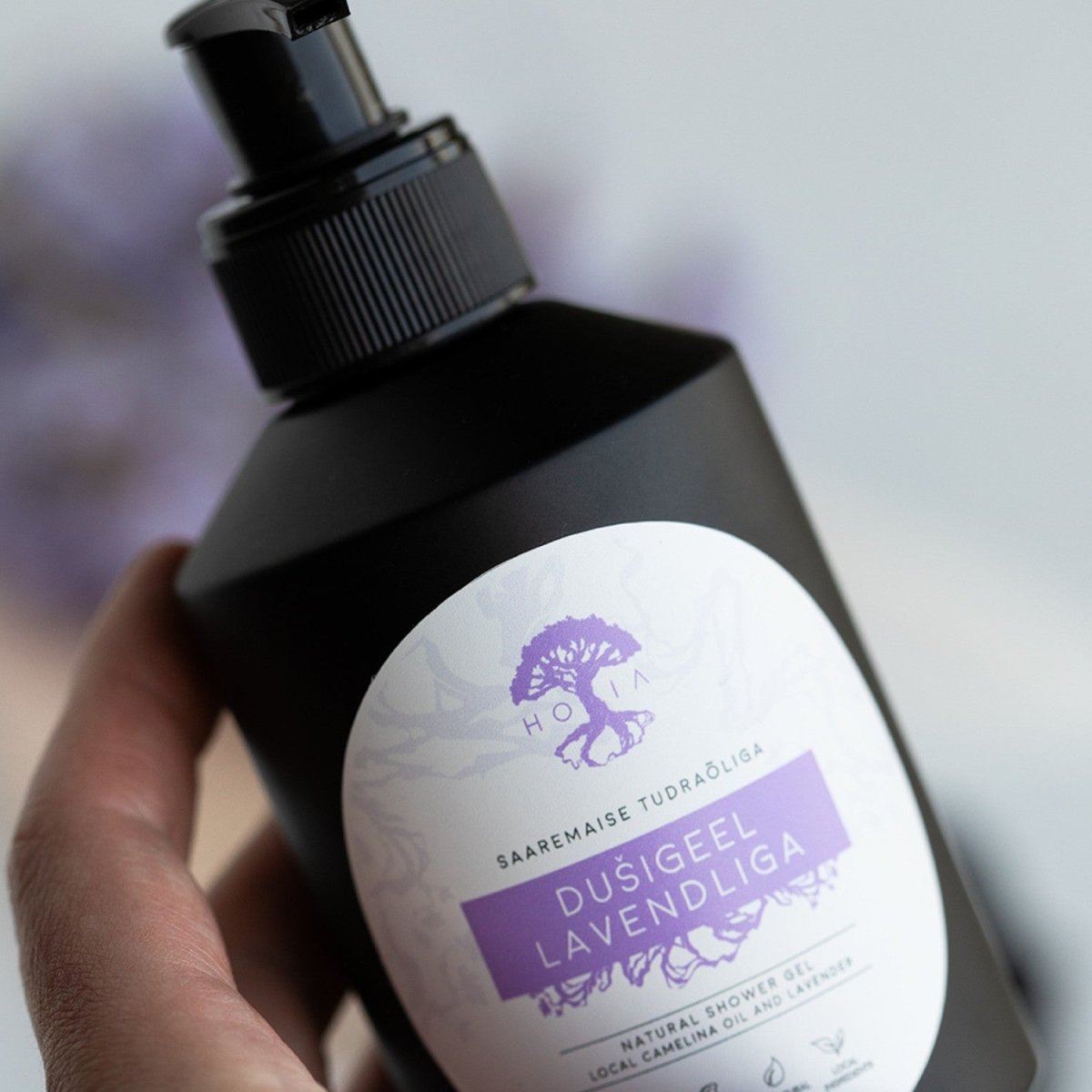 Hand håller svart pumpflaska med naturlig duschtvål lavendel från HOIA, 200 ml