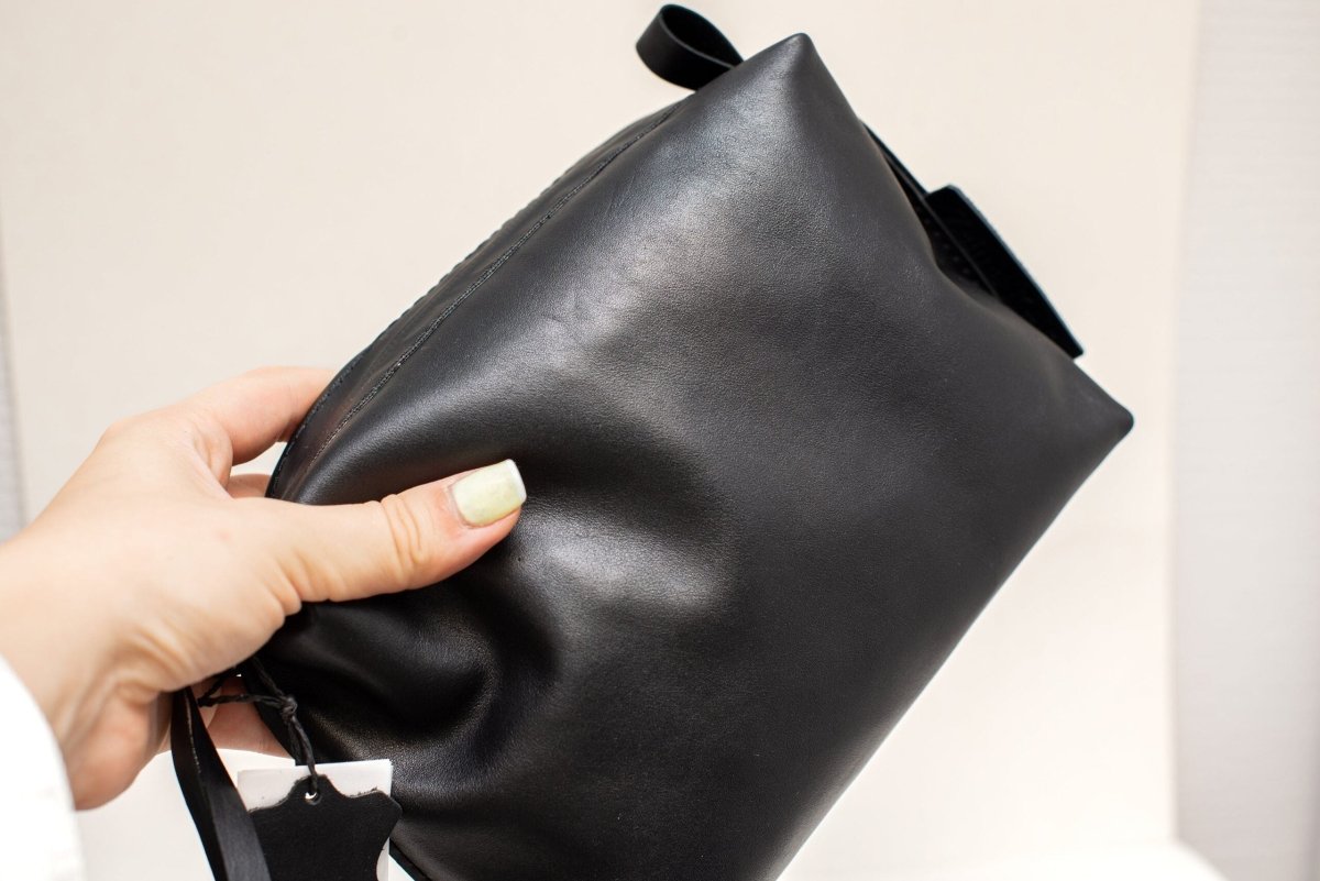 Necessär i läder, svart - medium hålls i hand, visar mjuk svart läderyta med dragkedja och handtag
