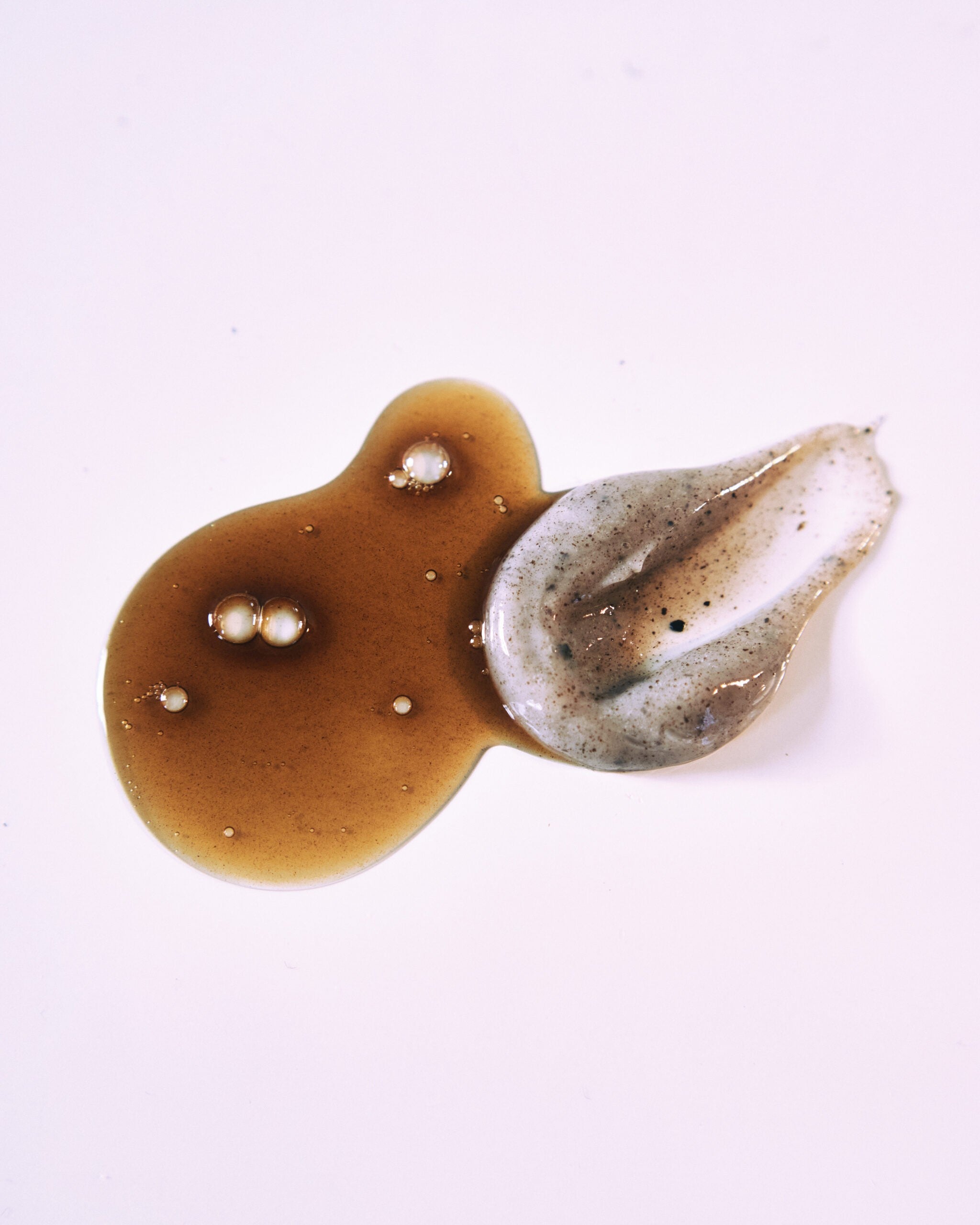 Nurme Torvschampo i brun gelkonsistens med pärlor och grå lerspatel på ljus bakgrund