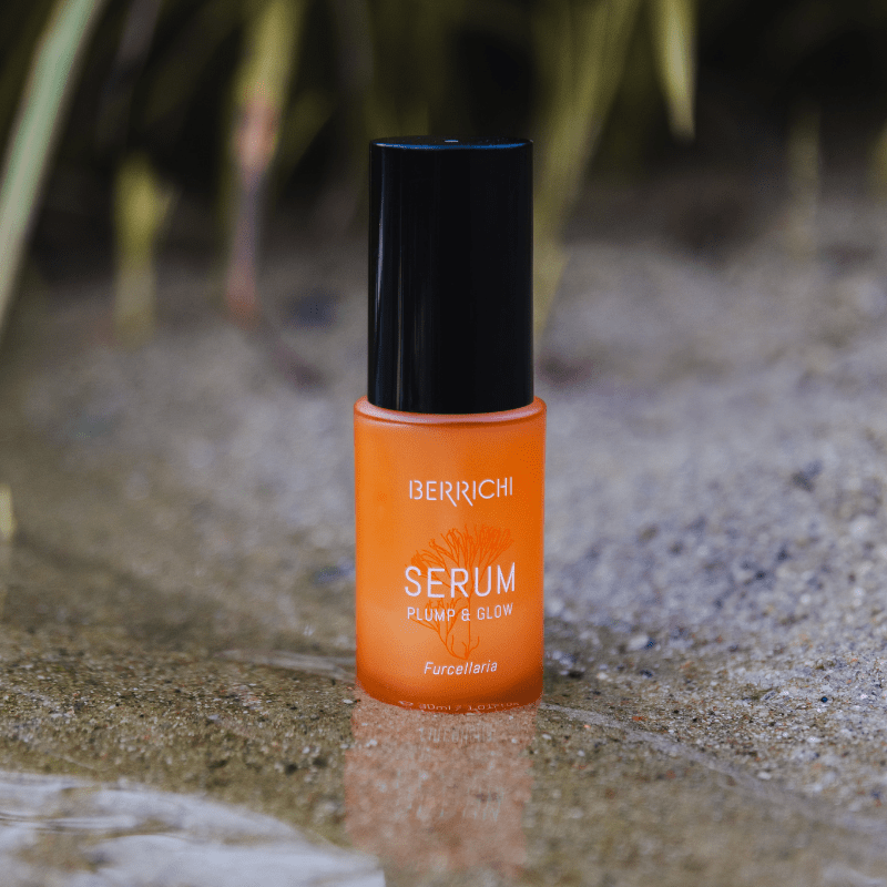 Orange serum med svart pump på stengrund med naturlig bakgrund - Återfuktande serum 30ml från Berrich