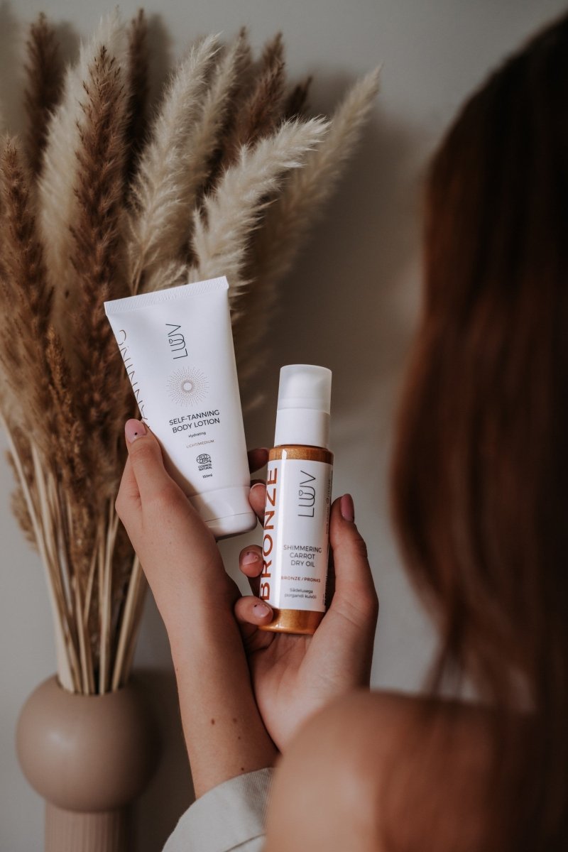 Shimmering Carrot Dry Oil Bronze i vit flaska med pump och kopparfärgad etikett, hålls i hand bredvid vit tub