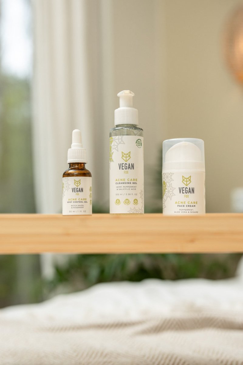 Vegan Fox Acne Care Face Set med tre produkter: brun droppflaska, genomskinlig pump och vit burk på träbord