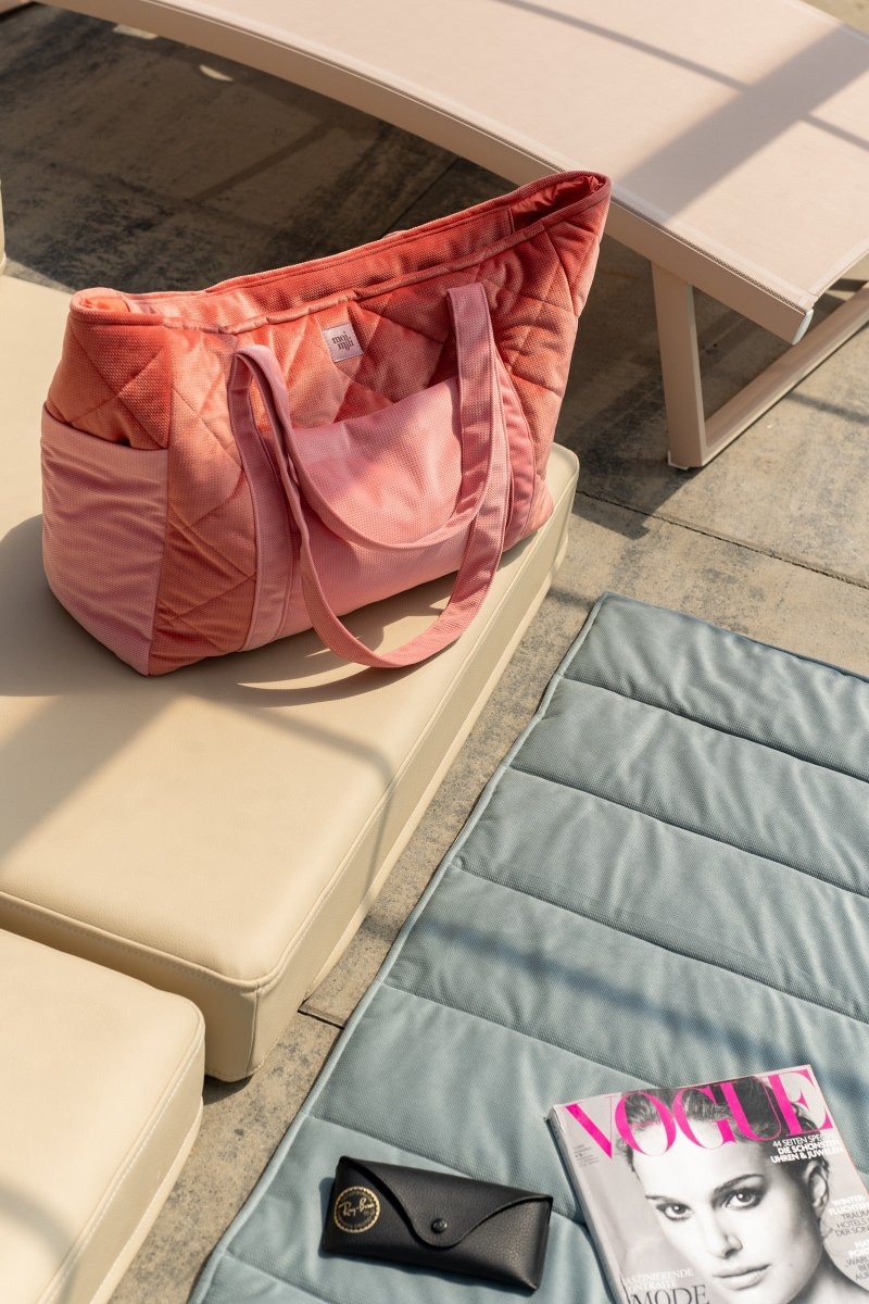 Handgjord weekenderbag i rosa sammet från Moi Mili på solstol vid poolen, bredvid Vogue-magasin