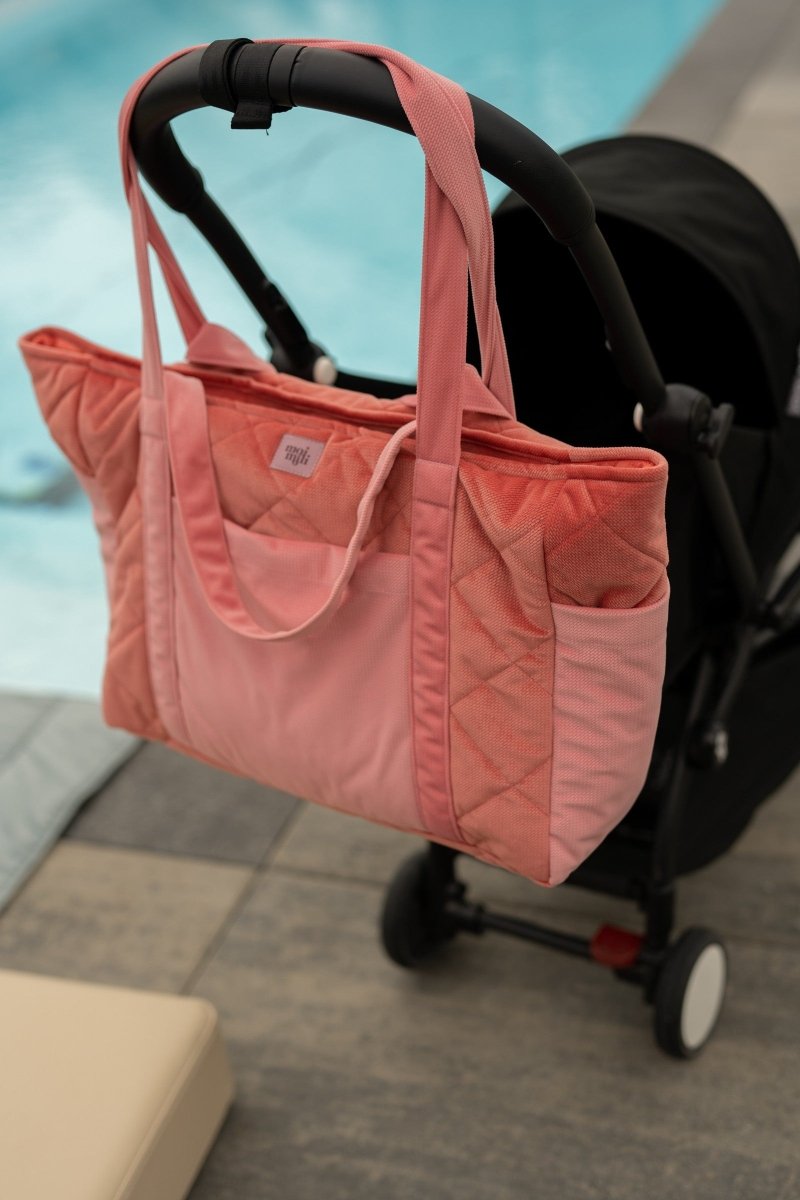 Handgjord weekenderbag i rosa sammet från Moi Mili hängandes på barnvagn vid pool